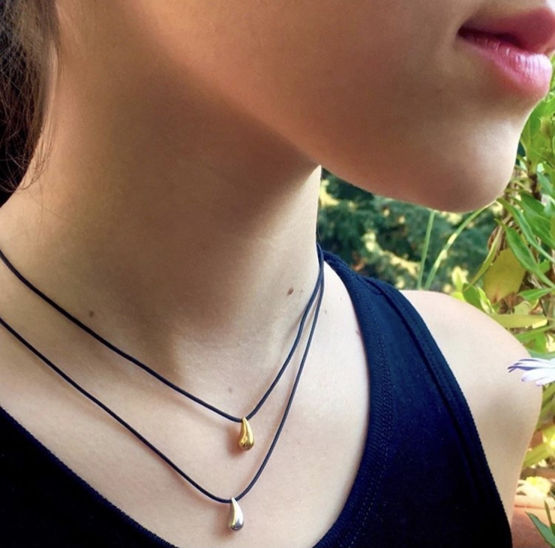 Little drop - gold pendant on a black cord.