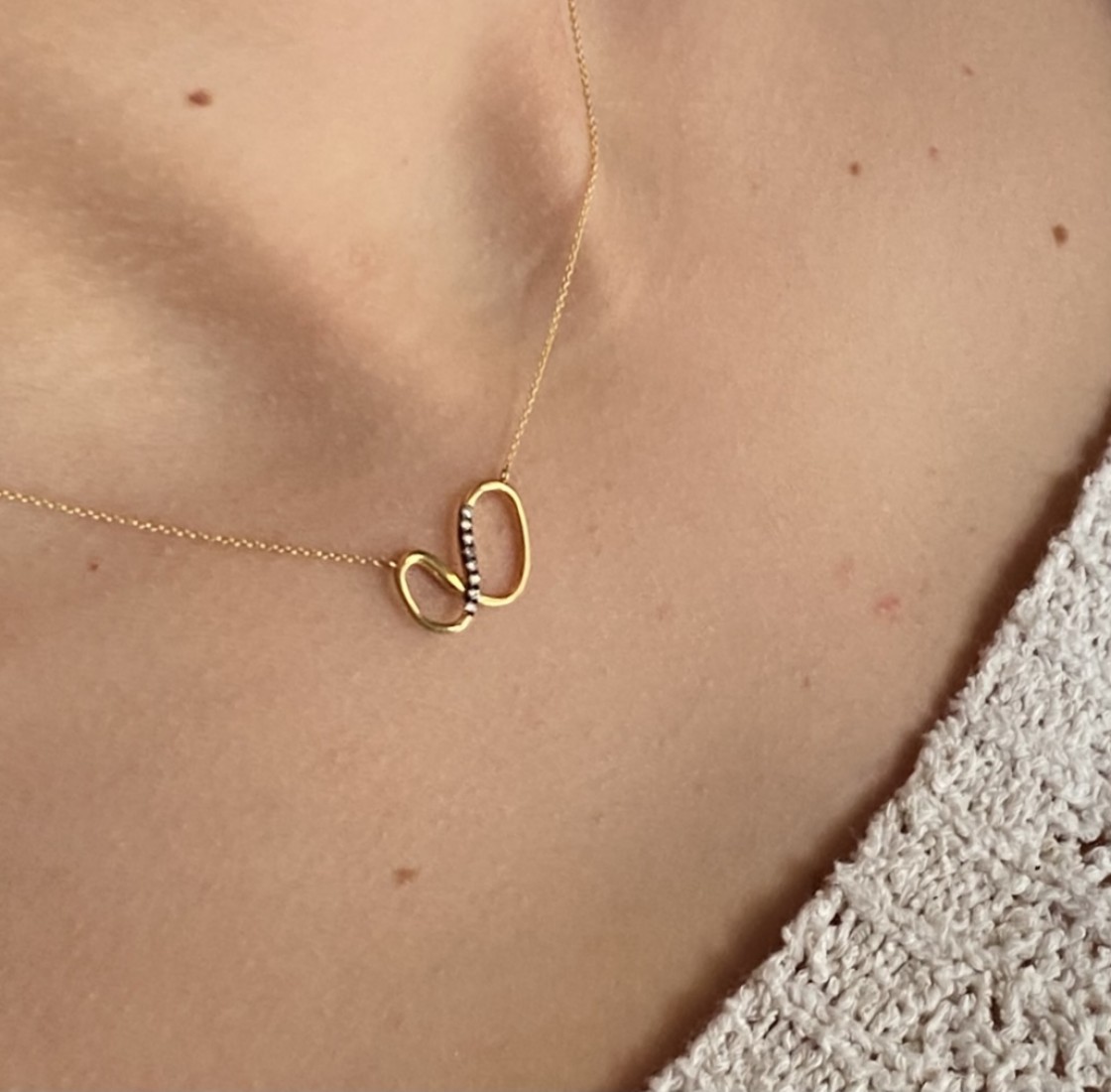 Small gold infinity charm inlaid with white brilliant cut diamonds, delicate gold chain.